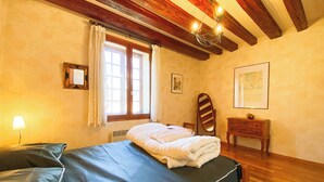 Une chambre à coucher avec un lit, une table de chevet, un miroir et une fenêtre avec des rideaux.
