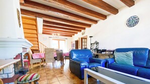 Un salon spacieux avec un canapé bleu, un coin repas avec des chaises en osier et une cuisine avec un comptoir en bois.