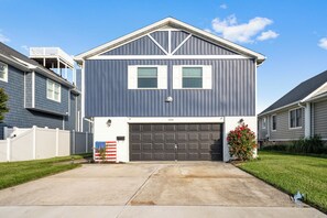 A two-story house with a garage, a small porch, and a well-maintained lawn.