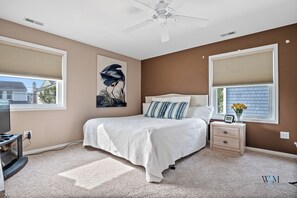 A bedroom with a bed, nightstand, and a ceiling fan.