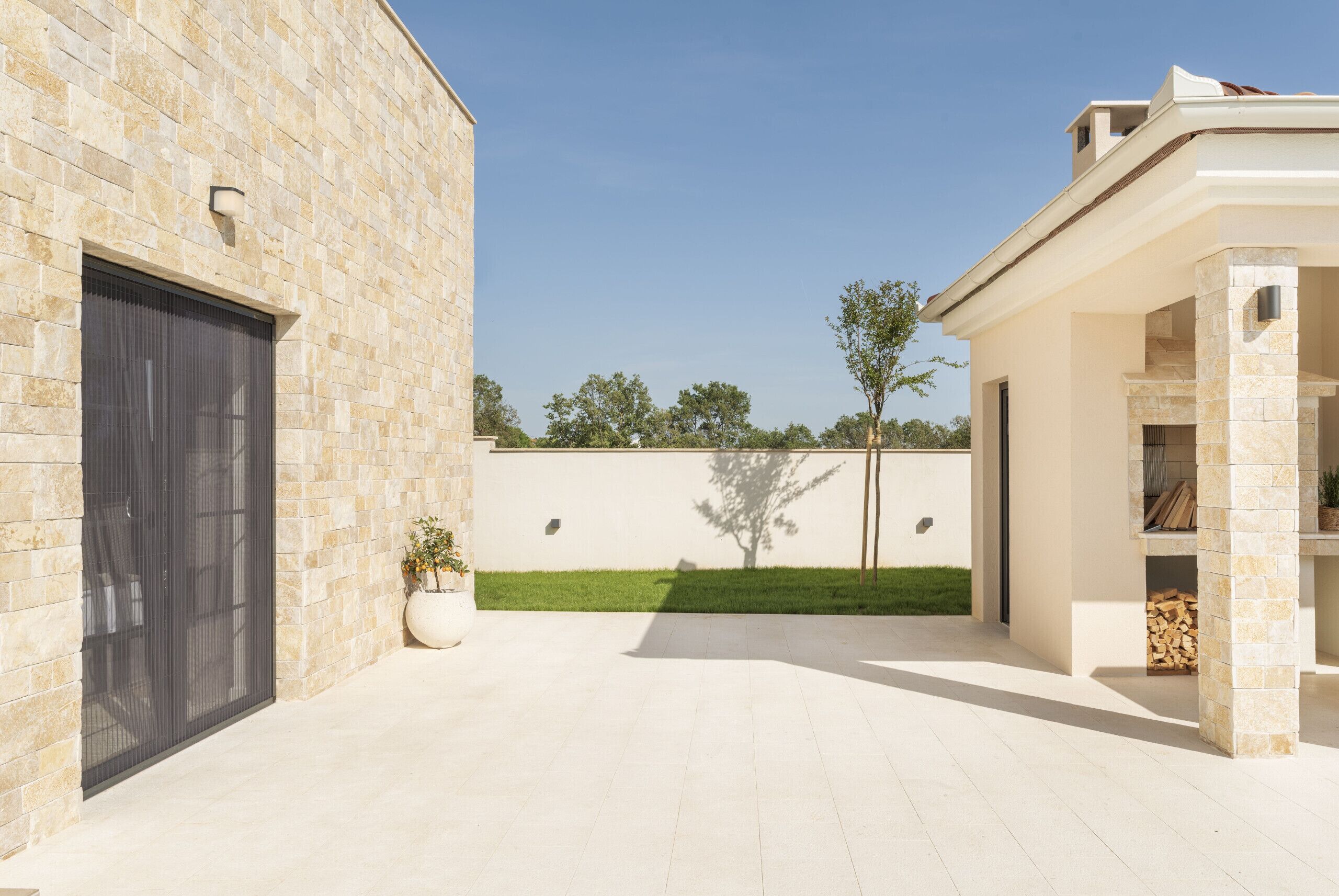 A modern building with a stone facade, a large garage door, and a covered patio area.