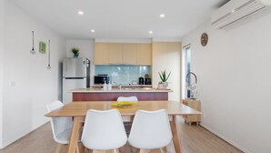 A modern kitchen with a central island, white chairs, and a dining table.