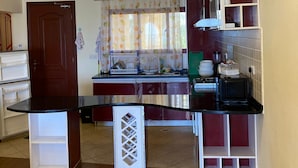 A compact kitchen with a central island, a microwave, and various storage cabinets. - The Penthouse Waterfronts (Mombasa)