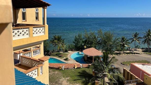 A hotel with a pool, palm trees, and a view of the ocean. - The Penthouse Waterfronts (Mombasa)