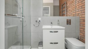 A modern bathroom with a glass shower enclosure, a white sink, and a toilet. - Comfortable Studio in the Center | Close to the Old Market and WiFi (Poznan)