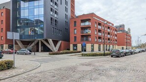 Un edificio moderno con facciata in vetro e un'area di parcheggio con auto.