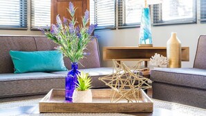 A living room with a sofa, a blue vase with plants, a geometric decorative piece, and a lamp. - The Loft - Lounge with Grill and Hot Tub! (South Pittsburg)