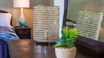 A room with a bed, a lamp, a decorative lamp, a mirror, and a potted plant.