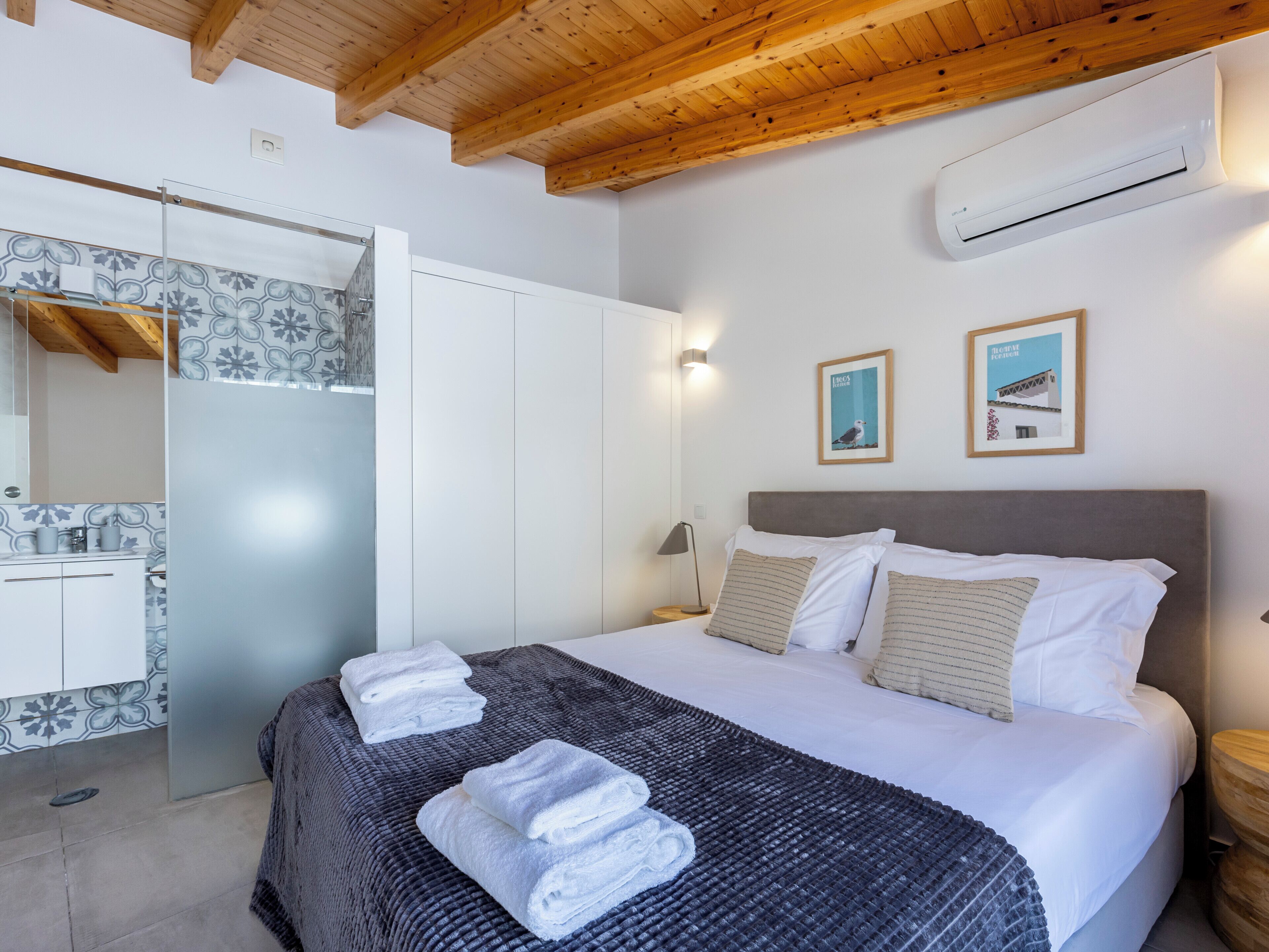 A bedroom with a bed, a wardrobe, and an air conditioning unit.