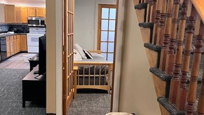 Un pasillo estrecho con un banco de madera y vistas a un dormitorio con cama y ventana.