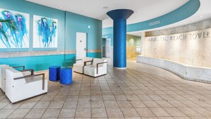 Un hall con paredes azul verdosas, un mostrador de recepción y un pilar grande.