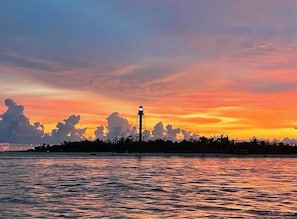 A lighthouse at sunset with a calm sea and a clear sky.
