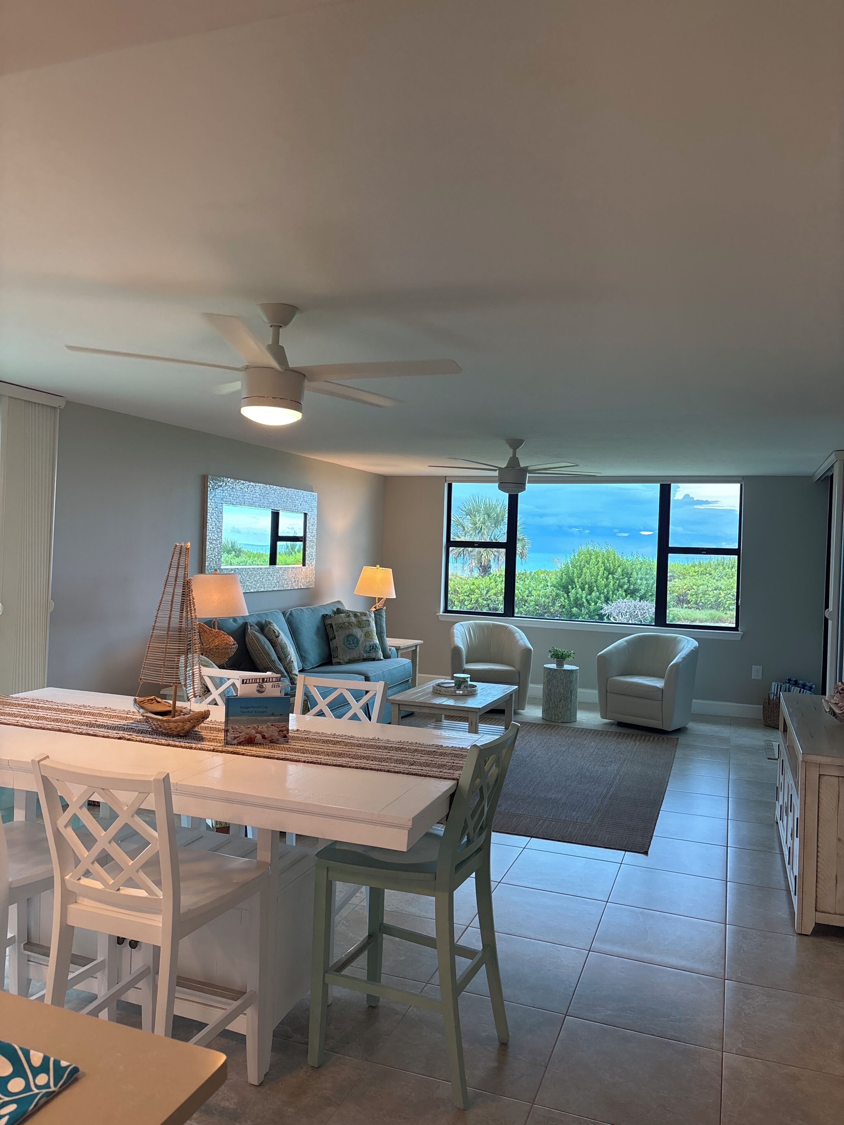 A spacious living area with a dining table, chairs, a sofa, and a view of the ocean.