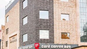 A modern building with a cafe named 'Cafe Coffee Day' on the ground floor. - Hotel Mani Ram Palace (Agra)