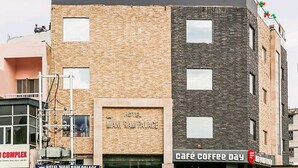 A multi-story building with a sign for "Hotel Man Ram Palace" and a café named "Café Coffee Day" on the ground floor. - Hotel Mani Ram Palace (Agra)