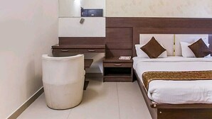 A bedroom with a bed, bedside tables, a mirror, and a trash bin. - Hotel Mani Ram Palace (Agra)