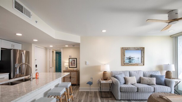 A modern kitchen with a central island, bar stools, and a dining area. - Seaside Serenity-2BD 2BA condo w/ pool, parking, tennis courts, near beaches (Key West)