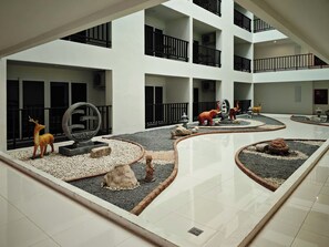 Experience the serene atmosphere of our multi-level atrium, featuring a central courtyard with decorative statues and a striking circular sculpture.