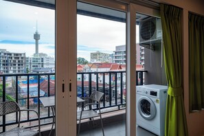 Enjoy the city view from this balcony with a washing machine, table, and two chairs.