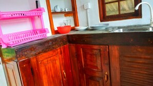 A kitchen with wooden cabinets, a sink, and a window with a view. - Green View Guest (Mirissa)