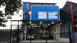 A building with a blue facade, a gated entrance, and a covered parking area. - Arrecifes 2 (Cartagena de Indias)