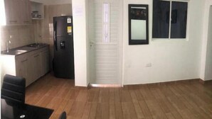 A compact kitchen with a refrigerator, a sink, and cabinets. There is a door with a window and a small window on the wall. - Arrecifes 2 (Cartagena de Indias)
