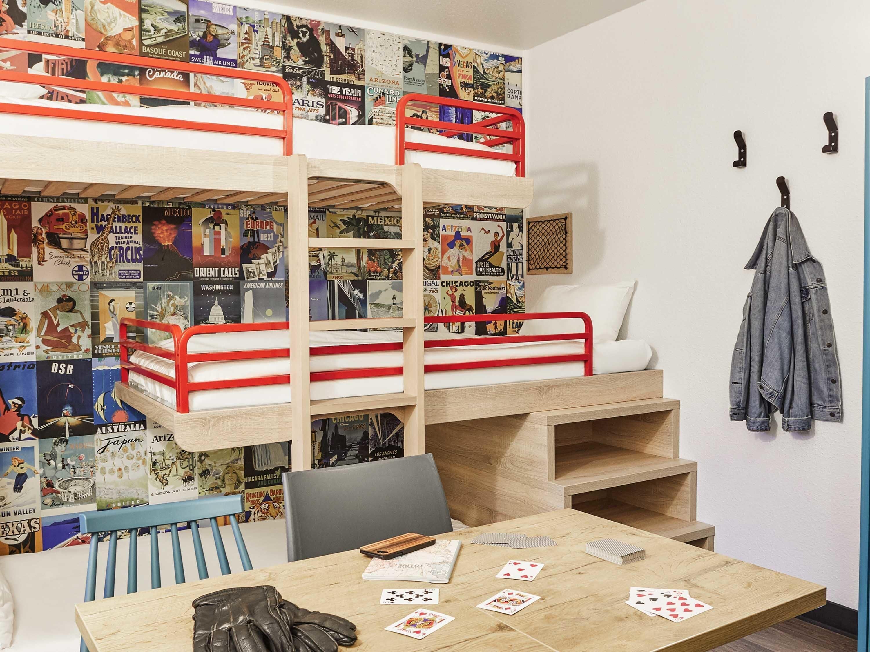 A bunk bed room with posters, a desk with playing cards, and a jacket hanging on the wall.
