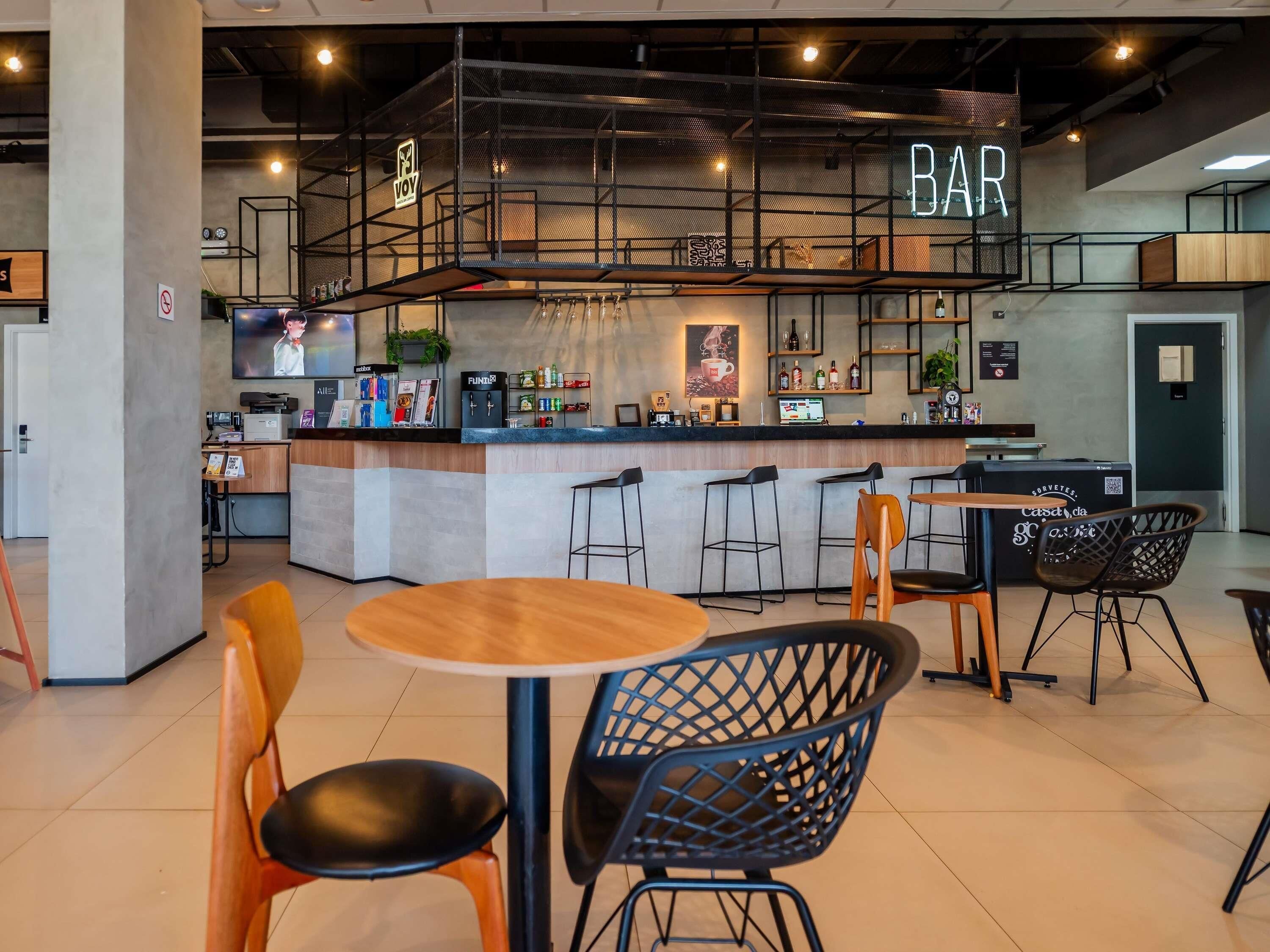 A modern bar area with a counter, stools, and a neon sign.