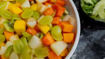Una ciotola di macedonia con kiwi, mango e uva ben visibili.
