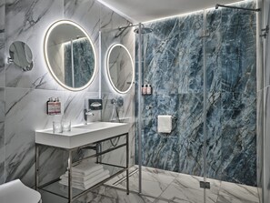 A modern bathroom with marble walls, a glass shower enclosure, and dual vanity mirrors. - Mövenpick Grand Hotel Wroclaw (Wroclaw)