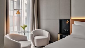 A hotel room with a bed, two armchairs, a small table, a floor lamp, and a fireplace. - Mövenpick Grand Hotel Wroclaw (Wroclaw)