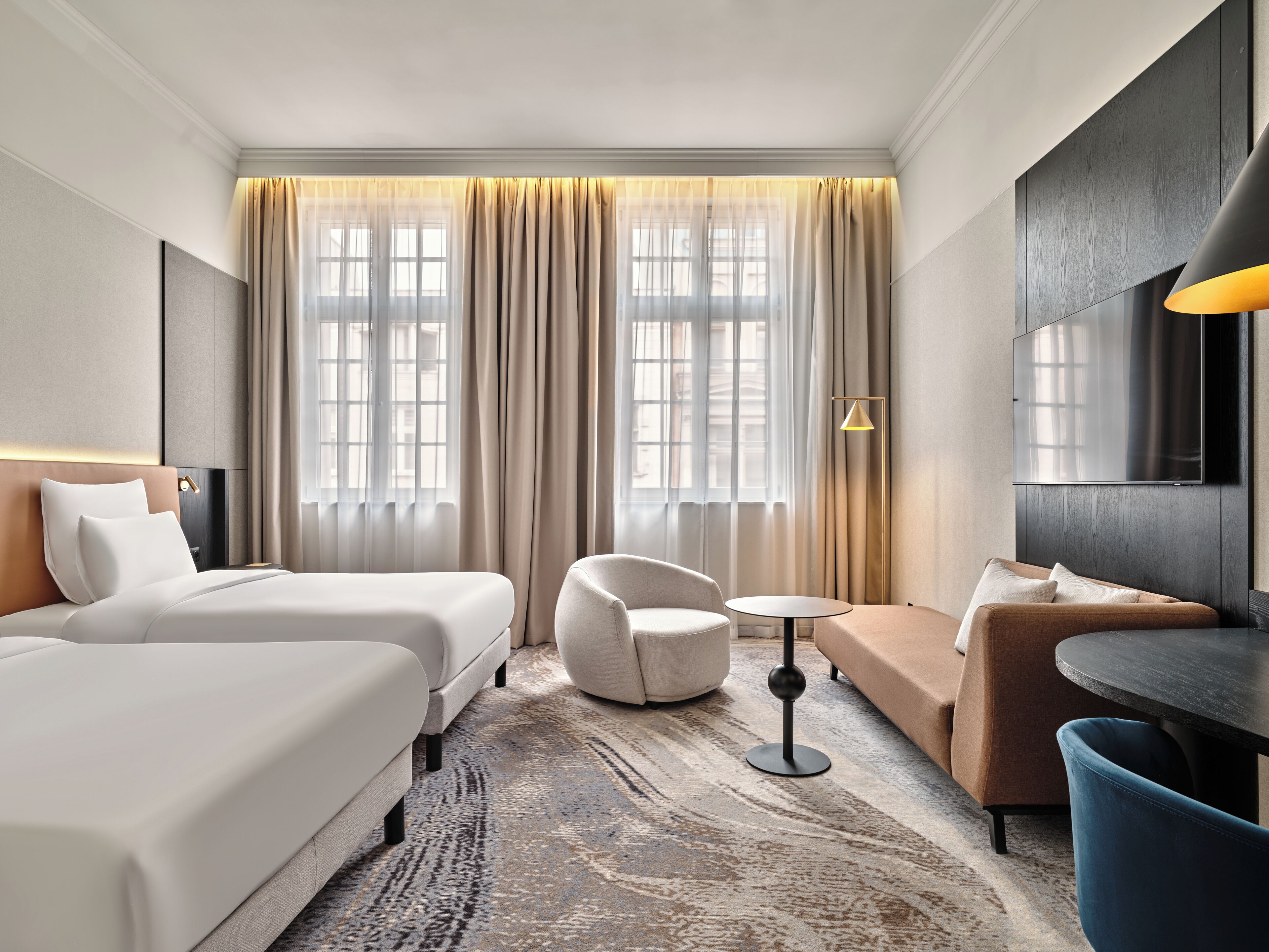 Habitación de hotel con dos camas, un sofá, una mesa redonda y una silla.