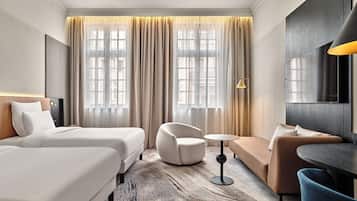 Habitación de hotel con dos camas, un sofá, una mesa redonda y una silla.