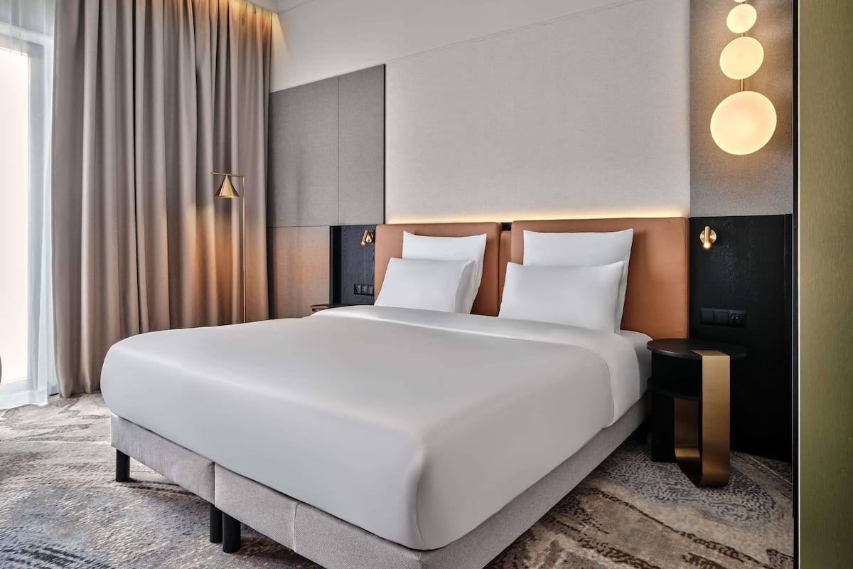 Ein großes Bett mit Holz-Kopfteil, zwei Nachttische und eine Wandleuchte.