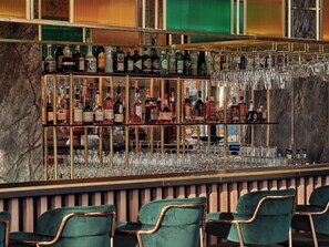 Una zona de bar con múltiples estantes llenos de botellas de licor y una variedad de vasos.