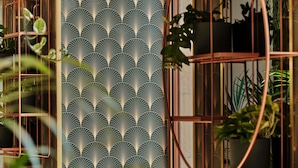A room with a patterned wallpaper, a window with a view of greenery, and a plant shelf. - Mövenpick Grand Hotel Wroclaw (Wroclaw)