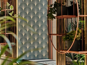 A room with a patterned wallpaper, a window with a view of greenery, and a plant shelf. - Mövenpick Grand Hotel Wroclaw (Wroclaw)