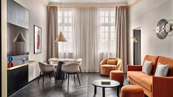 A modern living room with a sofa, ottoman, and a dining area with chairs and a table.
