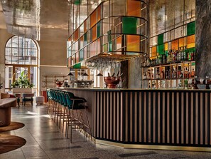 A bar area with a curved counter, bar stools, and a variety of bottles and glasses. - Mövenpick Grand Hotel Wroclaw (Wroclaw)