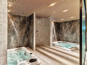 A modern bathroom with two hot tubs, marble walls, and a wooden ceiling. - Mövenpick Grand Hotel Wroclaw (Wroclaw)