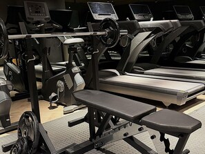 A gym with treadmills, weight machines, and a bench. - Mövenpick Grand Hotel Wroclaw (Wroclaw)