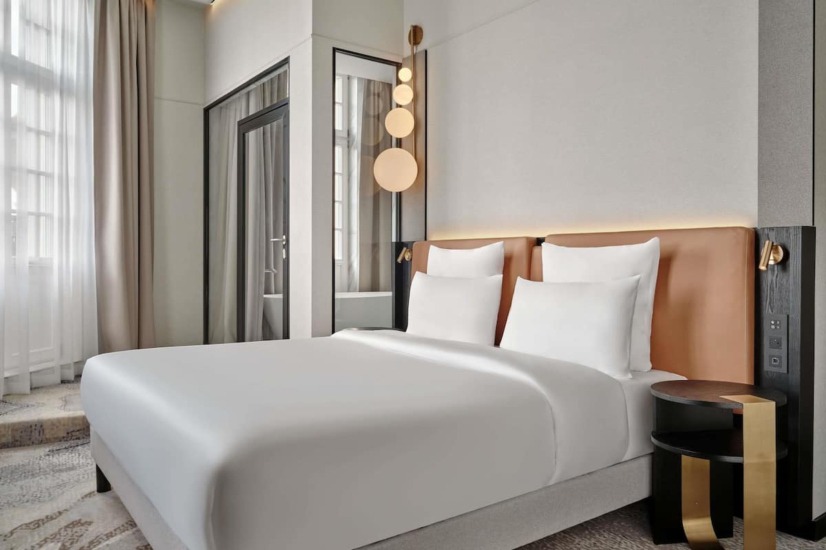 Ein modernes Hotelzimmer mit einem großen Bett, einem Nachttisch und einem Spiegel.