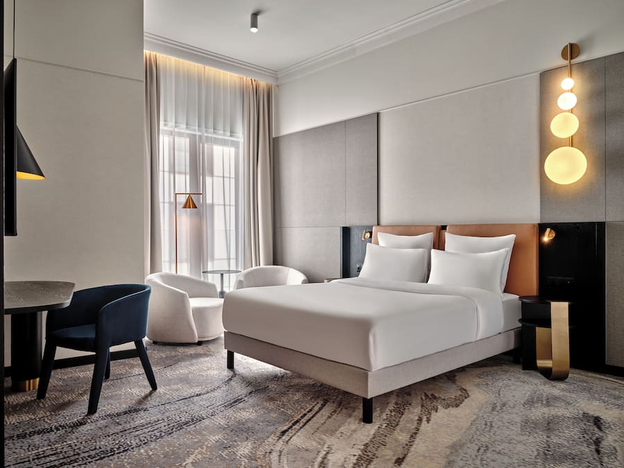 Una habitación de hotel moderna con una cama grande, un escritorio, una silla y un sofá.