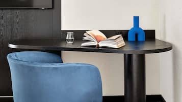 Una mesa pequeña y redonda con un libro, un vaso de agua y un objeto azul encima.
