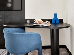 A small, round table with a book, a glass of water, and a blue object on it.