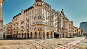 Un edificio histórico de varios pisos, con amplias ventanas y una destacada torre con reloj.