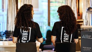Two individuals seated at a table with laptops, wearing black shirts with "TRIBE" printed on the back. - Tribe Paris Clichy  (Clichy)