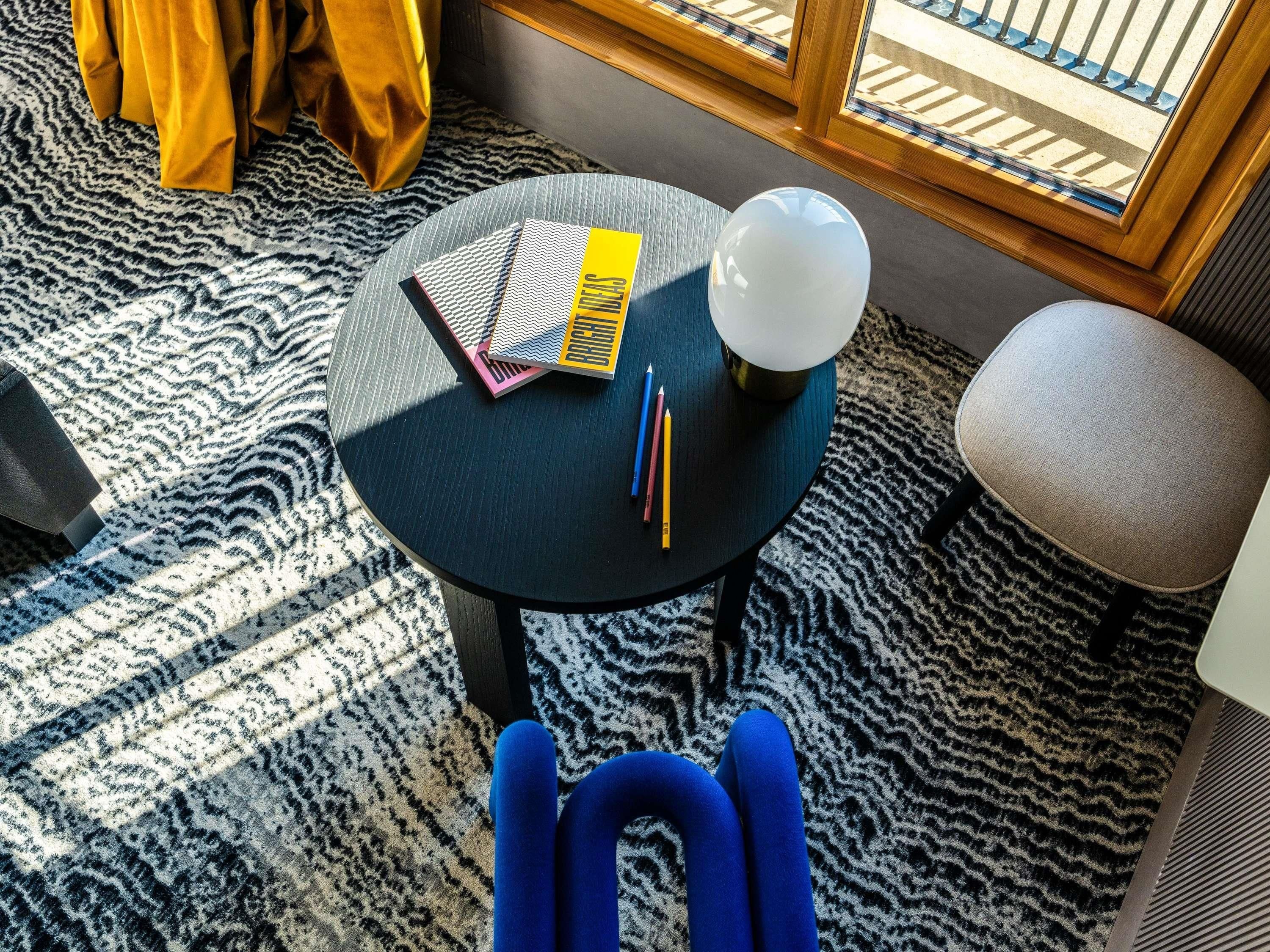 A round table with a book, pencils, and a lamp.