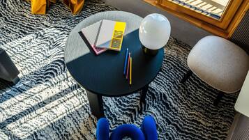 A round table with a book, pencils, and a lamp.