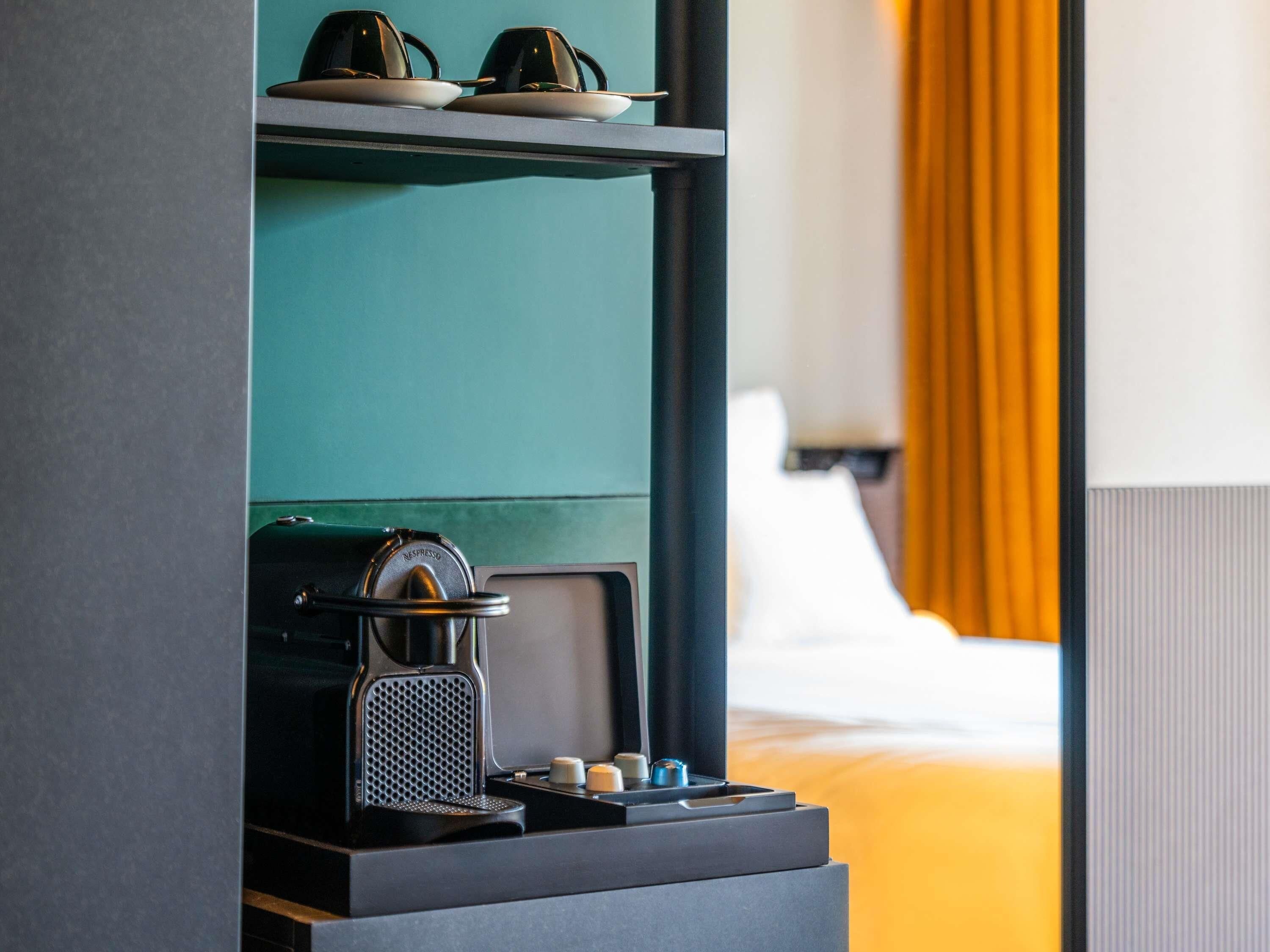 A compact coffee machine with a single cup holder and a small selection of coffee pods.